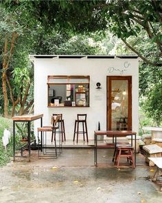 a small white building with tables and chairs outside