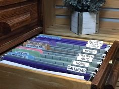 a wooden box filled with lots of folders next to a plant and potted plant