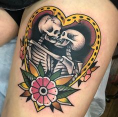 a woman's thigh with a skull and flower tattoo on it