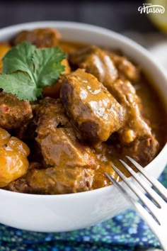 a close up of a bowl of food on a table with a fork in it