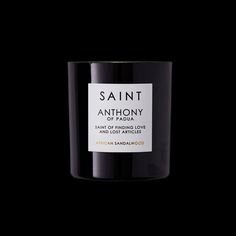 saint anthony candle in black glass with white label on the front and side, against a dark background