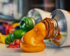 an orange liquid pouring out of a bottle onto the ground next to other colorful bottles