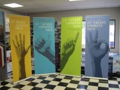 four different colored banners with hand prints on them in front of a checkered floor