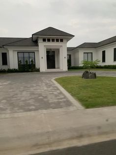 a large white house sitting on top of a lush green field next to a driveway