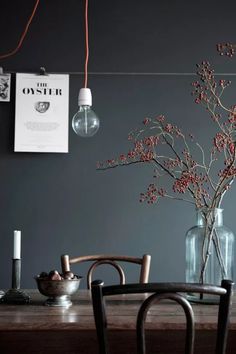 a wooden table topped with two vases filled with flowers next to a light bulb