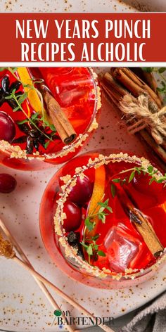 two glasses filled with red liquid and garnished with herbs, cinnamon sticks and cherries