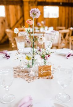 the centerpieces on this table are made from wood and glass vases with flowers in them