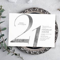 the wedding stationery is displayed on top of a silver plate with greenery around it