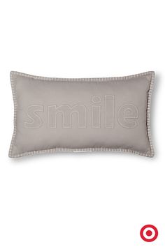 a gray pillow with the word smile on it and a red target in the background