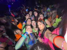 a group of young women standing next to each other in front of a crowd at a nightclub