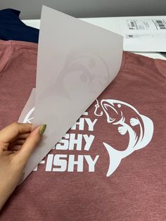 someone is cutting out some paper on top of a t - shirt that says why they fish