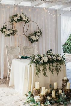 the table is set up with candles and greenery for an elegant wedding reception in white