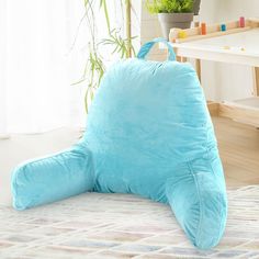 a large blue pillow sitting on top of a white rug next to a potted plant