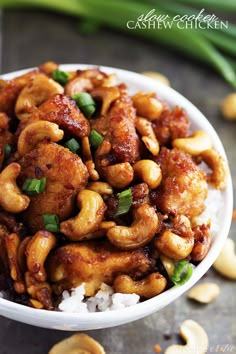 chicken and cashews in a white bowl with rice on the side, as well as green onions