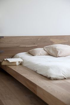 a wooden bed with white sheets and pillows on it's headboard is shown