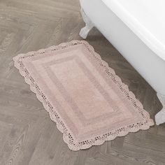 a bathroom rug on the floor next to a bath tub