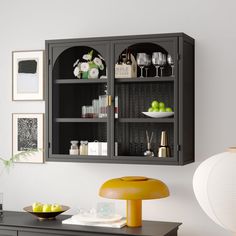 a black cabinet with glass doors on the top and shelves above it in a room