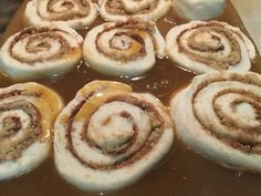 cinnamon rolls with icing sitting on top of a pan