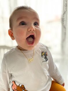 a baby wearing a winnie the pooh t - shirt is making a funny face