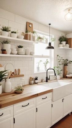 a kitchen filled with lots of white cupboards and counter top next to a window