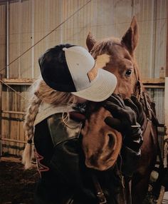 a person wearing a hat hugging a horse