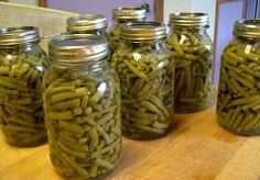 several jars filled with green beans sitting on top of a wooden table