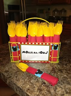 a table topped with yellow and red plastic utensils next to a sign that says moust - ka - lou