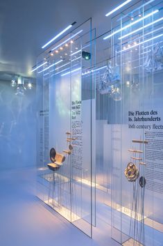 an exhibit with chairs and other items in glass cases on the wall, all lit up by lights