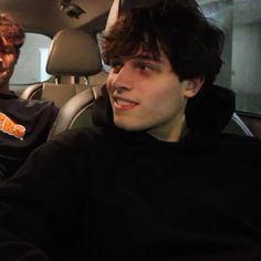 two young men sitting in the back seat of a car