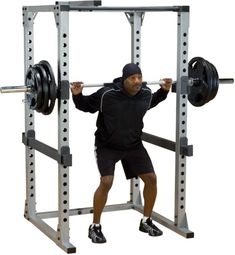 a man is squatting in front of a barbell rack with one hand on his hip