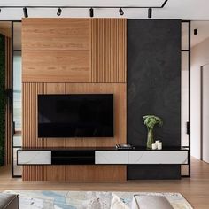 a modern living room with wood paneling and black walls, large television on the wall