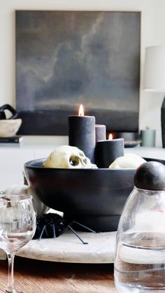 a table topped with candles and bowls filled with food next to wine glasses on top of a wooden table