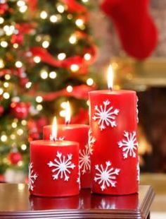 three red candles sitting on top of a table next to a christmas tree