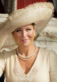 a woman wearing a large hat and pearls