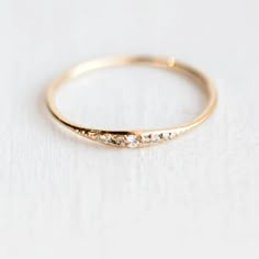 a gold ring with three small diamonds on the top and bottom, sitting on a white surface