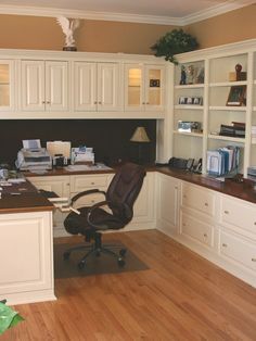 an office with white cabinets and wooden floors