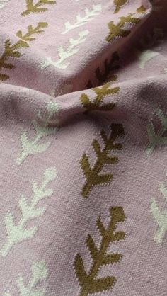 a close up view of a pink fabric with green leaves and dots on it's edges