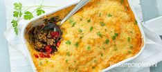 a casserole dish with meat and vegetables in it on a white napkin next to a spoon