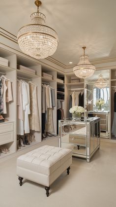 Glamorous white walk in closet featuring crystal empire chandeliers, mirrored island, and tufted ottoman. Closets With Vanity, Luxury Dressing Room Beautiful Closets, Walk In Closet With Mirror, Closet Ideas Walk In, Luxury Walk In Closet Women, Closet Aesthetic Luxury, Dressing Room Modern, Classic Dressing Room