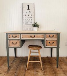 an old desk with two drawers and a stool in front of it on a wooden floor