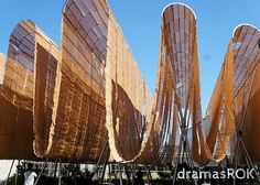 people are standing in front of an art installation made out of wood and metal strips