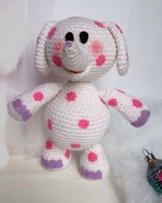 a crocheted dog sitting next to a christmas ornament on a white surface