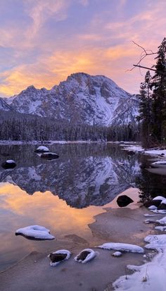 the sun is setting over a mountain lake