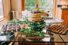 a table topped with lots of desserts next to a glass top table filled with cakes and muffins