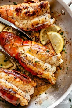 two cooked lobsters in a pan with lemon wedges