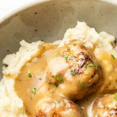 some meatballs and gravy on top of mashed potatoes in a bowl