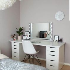 a bedroom with a desk, mirror and white chair in front of the bed is shown