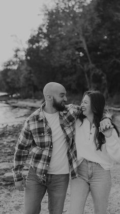 a man and woman are walking together on the beach with trees in the back ground