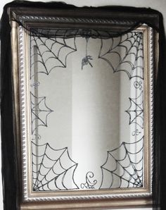 a spider web is hanging on the wall in front of a mirror that has been decorated with black and silver trim