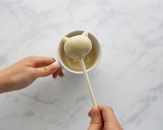 a person holding a lollipop on a stick in front of a marble counter top